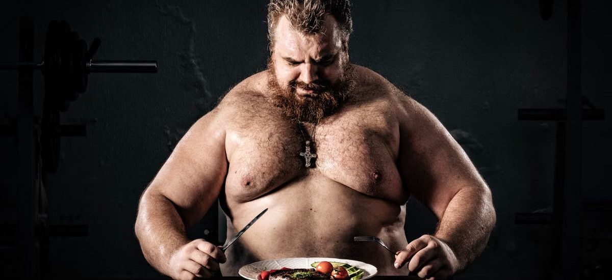 Shirtless muscular man eating a nutritious meal, symbolizing strength and health.