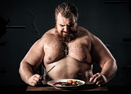 Shirtless muscular man eating a nutritious meal, symbolizing strength and health.